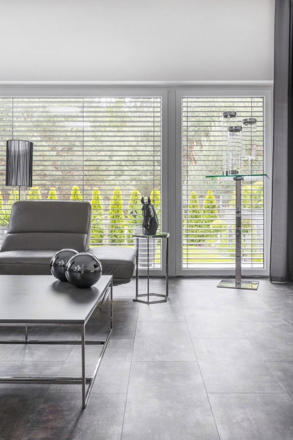 Ground-floor living room of a UAE villa with large windows covered by blinds facing the garden